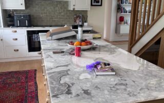 Grey-and-white Dover White quartzite kitchen island beneath brass-toned pendant lights